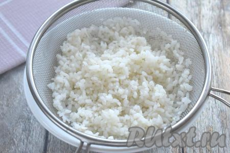 Слоёное тесто (я купила дрожжевое слоёное тесто, но отлично подойдёт и бездрожжевое слоёное тесто) достаём из морозилки и оставляем размораживаться при комнатной температуре. Пока тесто размораживается, приготовим начинку для курника. Для этого промываем рис под проточной водой, лишнюю воду сливаем. В кастрюле доводим до кипения 200-250 миллилитров воды, выкладываем промытый рис, перемешиваем. Снова даём воде закипеть, добавляем соль, уменьшаем огонь и варим рис до готовности (минут 20-25). Рис, сварившийся до готовности, откидываем на сито, даём немного остыть.