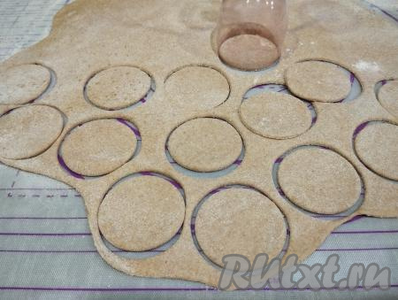 Каждую часть заварного теста из цельнозерновой муки раскатываем скалкой достаточно тонко. Вырезаем из теста кружочки стаканом диаметром 5 сантиметров. Остатки теста для пельменей собираем, раскатываем и вырезаем ещё кружочки.