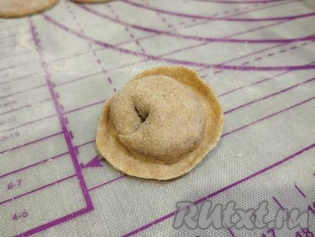 Затем соединяем противоположные концы заготовки, формируя округлый пельмешек.