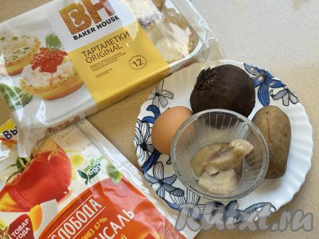 Подготовить продукты для приготовления селёдки под шубой в тарталетках. Картошку, не очищая от кожуры, выложить в кастрюлю, залить полностью водой и отварить до готовности (в течение минут 25 с момента закипания воды). В отдельную кастрюлю выложить свеклу в кожуре, тоже залить полностью водой и отварить до готовности (в течение 50-70 минут с момента закипания воды). Полностью готовые варёные овощи будут легко прокалываться ножом. Яйцо отварить в течение 10 минут с момента закипания воды. Варёные яйцо, свеклу и картофель полностью остудить. Песочные тарталетки для салата можно купить практически в любом продуктовом магазине.&nbsp;