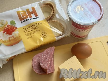 Подготовить продукты для приготовления тарталеток с колбасой и сыром в аэрогриле. Колбасу можно взять как варёную, так и копчёную или полукопчёную (у меня - полукопчёная). Сметана подойдёт любой жирности (я взяла жирностью 20%). Песочные тарталетки для этой закуски можно купить практически в любом продуктовой магазине.