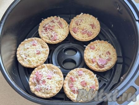 Разложить колбасно-сырную начинку по тарталеткам, заполняя их практически полностью. Я разложила по 10 тарталеткам. Поставить тарталетки на решётку в чашу аэрогриля в один слой. У меня поместились в чашу 6 тарталеток.