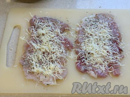 Сыр натереть на мелкой тёрке и равномерно разложить по 5 отбитым кусочкам куриного мяса.