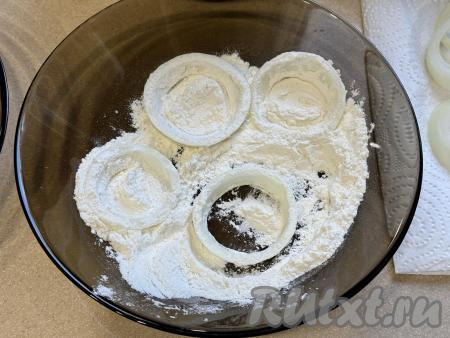 В отдельную глубокую тарелку всыпать муку. Обвалять луковые кольца в муке со всех сторон. Покрывать мукой, а затем и кляром нужно столько колец, сколько у вас одновременно поместятся в чашу аэрогриля.
