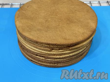 Готовый корж вместе с пергаментом переложить с противня на стол, дать остыть. Постепенно испечь и остудить все 15 коржей. Вот такая стопочка из 15 медовых коржей у меня получилась. "Обрезки" теста, которые выпекались вместе с коржами, будем использовать на следующий день для украшения карамельного медовика.