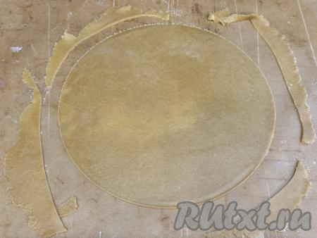 Коврик (или пергамент) вместе с кругом из теста и обрезами переложить на противень.