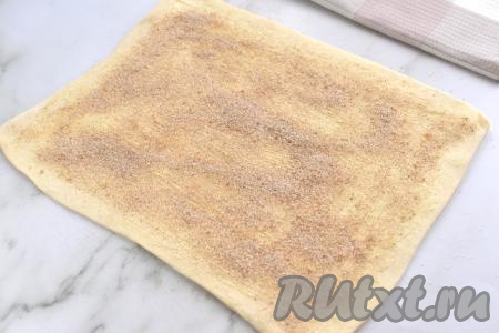 В небольшой ёмкости смешиваем сахар и корицу до однородности. Получившейся смесью из сахара и корицы посыпаем слоёное тесто, отступая от краёв примерно по 1 сантиметру.