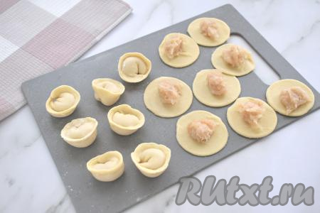 В центр каждого кружка из теста выкладываем по 0,5 чайной ложки куриной начинки. Плотно скрепляем противоположные края кружка над начинкой, формируя пельмень в виде полумесяца, а затем скрепляем концы полумесяца, формируя пельмень, как на фото. Постепенно лепим все пельмени. Тесто, оставшееся после вырезания кружков, снова собираем, раскатываем и тоже лепим из него пельмени. Из предложенного количества ингредиентов&nbsp;я слепила около 100 пельменей.