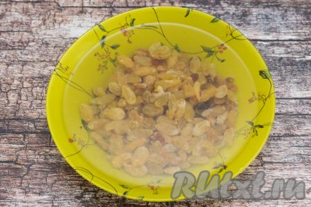 Прежде всего подготовим изюм. Его нужно будет промыть водой, затем переложить в глубокую тарелку, залить полностью кипящей водой и оставить распариваться на 5-7 минут.