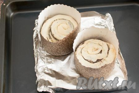 Противень для выпечки застелить фольгой, так как во время выпечки масло может вытекать из куличей. Куличи поместить в бумажные формы диаметром 11 сантиметров. Тесто должно занимать формы примерно на половину объёма. Поставить формы на противень с фольгой.