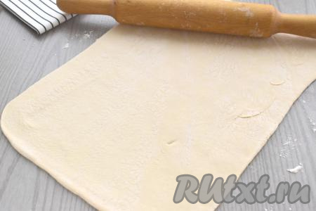Пласт размороженного слоёного теста выкладываем на стол, присыпанный мукой, и раскатываем скалкой в прямоугольник размером 23 сантиметра на 30 сантиметров.