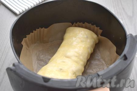 Чашу аэрогриля застилаем пергаментом, выкладываем заготовку штруделя с яблоками из слоёного теста швом вниз. В небольшую ёмкость разбиваем яйцо, взбиваем его силиконовой кисточкой до получения однородной массы. Получившейся яичной массой смазываем поверхность штруделя. Отправляем чашу в аэрогриль. Устанавливаем температуру 170 градусов, время - 25 минут.