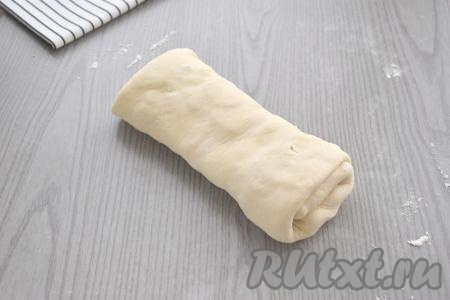 Начиная с подвёрнутой узкой стороны теста, сворачиваем тесто в рулет. Конец теста хорошо прижимаем к рулету.