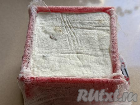 Взять плоскую тарелку, на неё ​​​​​​​выложить бумажное полотенце, сложенное в несколько слоёв. На тарелку поверх бумажного полотенца поставить пасочницу, застеленную марлей. Выложить творожно-сливочную массу в пасочницу, накрыть краями марли, которые свисают с краёв формы. Поверх марли поставить небольшой гнёт. В качестве гнёта я использовала достаточно тяжёлую разделочную доску, слегка прижав её. Но можно поставить поверх марли небольшую тарелку, а поверх неё разместить небольшую банку с водой. Убрать тарелку, на которой стоит пасочница, вместе с гнётом в холодильник на сутки. В процессе нахождения в холодильнике из&nbsp;творожной пасхи, приготовленной со сливками и сметаной,&nbsp;будет стекать лишняя жидкость, впитываясь в бумажное полотенце, находящееся под пасочницей. Намокшее бумажное полотенце нужно периодически менять на сухое бумажное полотенце, сложенное в несколько слоёв.&nbsp;