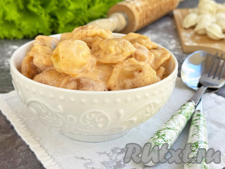 Жареные пельмени, приготовленные в сметане с сыром, разложить со сковороды по тарелкам и в горячем виде подать к столу.