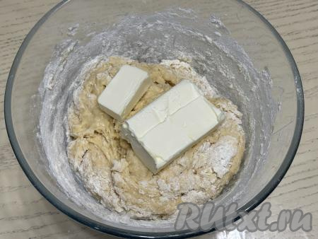 После того как в тесто в общей сложности будет вмешано 500 грамм муки, добавить в тесто кусочки сливочного масла комнатной температуры. Вмешать масло в тесто руками и начать добавлять по столовой ложке отложенные 100 грамм муки.