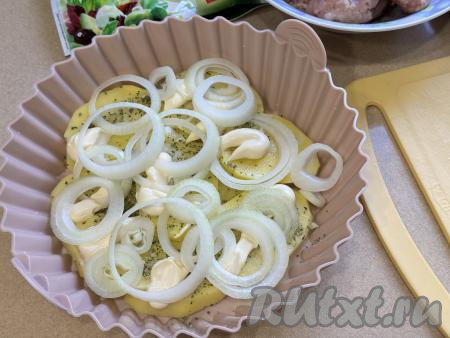 Смазать картошку майонезом. Лук нарезать на достаточно тонкие кольца, выложить поверх картошки.