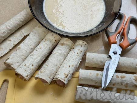 Завернуть сосиски в прямоугольники из лаваша, начиная с более узкого края.