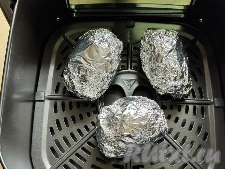 Каждый клубень картофеля, завёрнутый в фольгу, выложить на решётку в чашу аэрогриля. Можно запекать одновременно столько картошин, сколько у вас в один слой поместятся в чашу вашего аэрогриля. Я запекала 3 клубня.&nbsp;