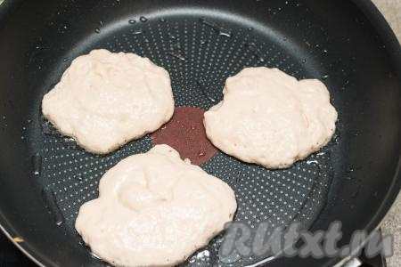 Сковороду хорошо прогреть с добавлением растительного масла. Выкладывать на сковороду примерно по 1 столовой ложке теста, формируя округлые оладушки. Оладьи, замешанные на фруктовом питьевом йогурте, жарить на огне ниже среднего до подрумянивания снизу (примерно 2 минуты).