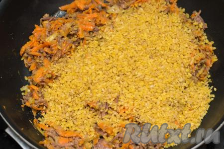 После того как овощи с тушёнкой обжарятся 3-4 минуты, всыпать в сковороду сухой булгур (предварительно промывать булгур не нужно).