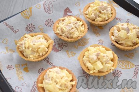 Тарталетки с начинкой ставим на противень (я решила предварительно застелить противень пергаментом, но это необязательно).