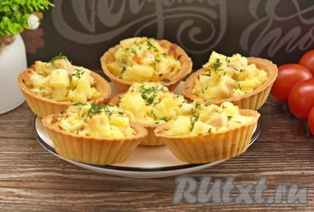 Достаём противень из духовки. По желанию, перед подачей тарталетки можно присыпать мелко нарезанным укропом. Тарталетки&nbsp;лучше всего сразу же подавать к столу, пока сыр аппетитно тянется, а ананасы и курица ещё тёплые, но и после остывания эта закуска остаётся очень вкусной.