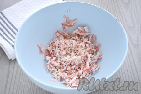 Крабовые палочки вынимаем из упаковки, натираем на крупной тёрке (или нарезаем на мелкие кубики), выкладываем в глубокую миску.