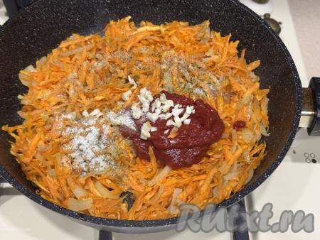 После того как морковь обжарится до мягкости, добавить в сковороду томатную пасту, мелко нарезанный чеснок, соль и чёрный молотый перец, можно всыпать и другие специи по вкусу.&nbsp;