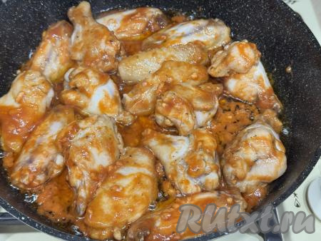 Перемешать крылья, покрывая их томатно-медовым соусом со всех сторон. Накрыть сковороду крышкой и томить крылышки 25 минут на медленном огне, периодически перемешивая. Если жидкости в сковороде будет недостаточно, тогда в процессе томления крыльев можно добавить к крыльям 2-3 столовых ложки воды).