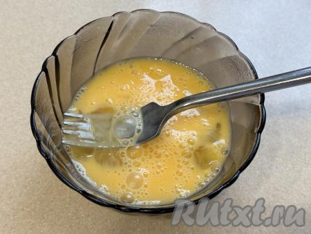 Пока обжаривается лук, в достаточно глубокую ёмкость вбить сырые яйца, взбить вилкой до однородности.&nbsp;