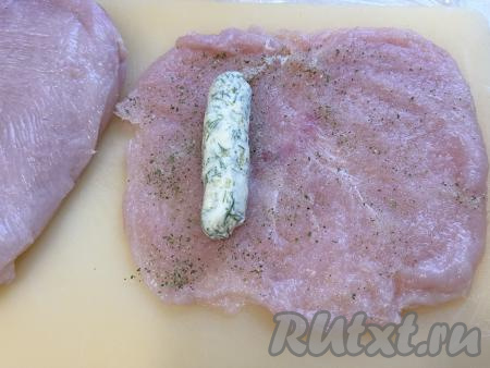 На каждую подготовленную куриную отбивную, ближе к узкому краю, выложить подмёрзшее масло, заранее освободив его от пищевой плёнки.