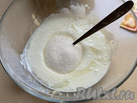 В миску с кефиром и маслом всыпать сахар, хорошо перемешать кефирную смесь столовой ложкой (или лопаткой).