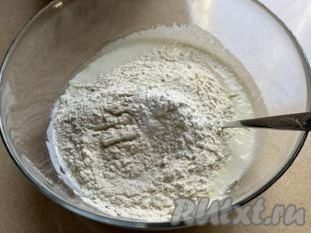 Отмерить муку и просеять. Всыпать в миску с кефирной массой 300 грамм просеянной муки и весь разрыхлитель.