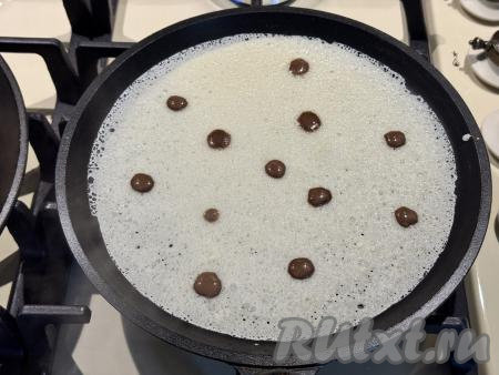 Сковородку хорошо разогреть на достаточно сильном огне, смазать растительным маслом. Влить в сковороду небольшой половник теста, равномерно распределяя тесто по дну сковороды. Сразу нанести горошины из шоколадного теста на блин при помощи шприца, выдавливая по капельке шоколадного теста, как на фото.