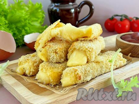 Аппетитные сырные палочки, приготовленные в панировке, достать из аэрогриля, переложить на тарелку и сразу подать к столу.
