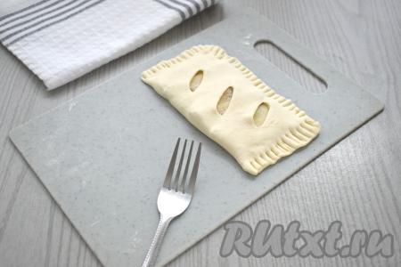 Стороной квадрата с разрезами накрываем сторону с начинкой. Вилкой тщательно скрепляем края слойки. Для того чтобы вилка не липла к тесту, можно периодически окунать зубцы вилки в муку. Аналогично формируем ещё 3 слойки с грушами.