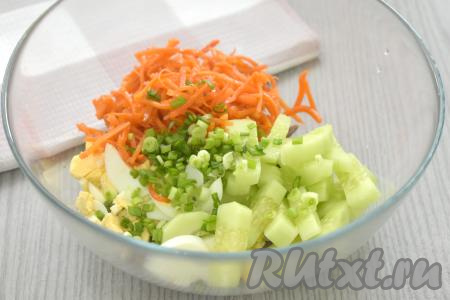 Зелёный лук моем, нарезаем. Корейскую морковь отжимаем от маринада, в котором она находилась. Длинные полоски моркови нарезаем на 3-4 части. В миску с салатом из свиного языка, яиц и огурца добавляем корейскую морковь и зелёный лук.