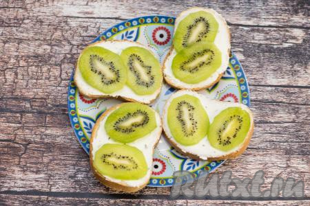Киви вымыть, очистить от кожуры. Нарезать киви на кружочки толщиной примерно 2-3 миллиметра. Выложить по 2 кружочка киви на каждый бутерброд.