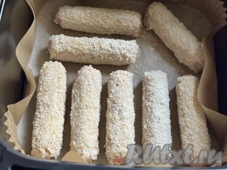 Чашу аэрогриля застелить пергаментом. Выложить подготовленную сосиску в кляре. Аналогично покрыть кляром все сосиски и тоже выложить их в один слой в чашу аэрогриля.&nbsp;