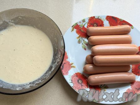 Понемногу подсыпая оставшуюся муку и каждый раз хорошо вмешивая её венчиком, замесить кляр, который по густоте будет напоминать достаточно жирный кефир. Как только добились нужной густоты кляра, значит не нужно больше добавлять муку. Сосиски очистить от слюды.