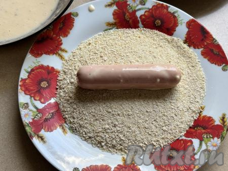 На тарелку насыпать панировочные сухари. Сосиску, покрытую кляром, обвалять со всех сторон в панировочных сухарях.