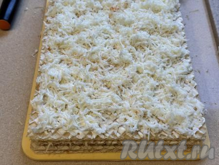 Варёные яйца разделить на белки и желтки. Корж с сыром накрыть четвёртым вафельным коржом. Смазать корж майонезом, равномерно разложить яичные белки, натёртые на крупной тёрке.