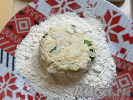 На отдельную тарелку насыпать 2 столовых ложки муки. Периодически смачивая руки водой, из каждой части теста сформировать круглые пирожки и обвалять их в муке со всех сторон. В результате получатся 7&nbsp;заготовок ленивых пирожков из творога с зелёным луком и яйцом.