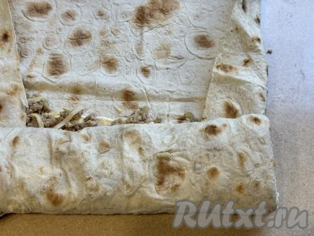 Подвернуть боковые края лаваша на начинку и, начиная с узкого края лаваша с начинкой, свернуть лаваш в рулет. В самом конце уже заворачиваем в рулет край лаваша без начинки.