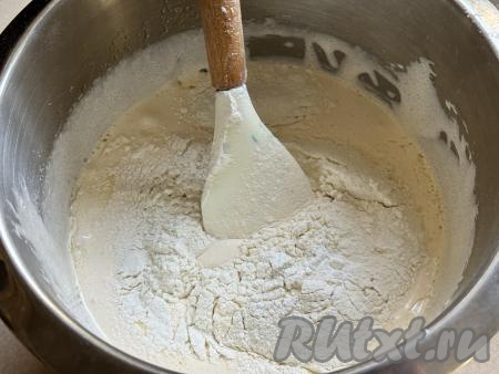 В чашу со взбитой яичной массой влить 125 миллилитров растительного масла, перемешать лопаткой (или столовой ложкой). Всыпать весь разрыхлитель и грамм 100 просеянной муки, перемешать лопаткой, полностью вмешивая муку и стараясь не сбить воздушность яичной массы. Понемногу начать добавлять оставшуюся муку, каждый раз полностью вмешивая её.