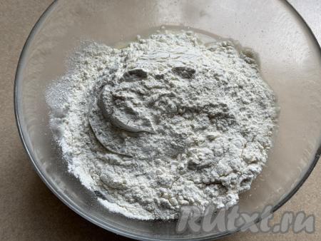 В миску с запенившейся дрожжевой смесью всыпать муку и соль. Вначале перемешивать тесто столовой ложкой, а затем собрать его в ком, замешивая пластичное тесто.