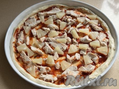 Ананасы нарезать на кусочки и выложить на тесто рядом с мясом курицы.