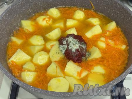 В сковороду с морковью, обжаренной до мягкости, добавить картошку, нарезанную на средние дольки, влить 700 миллилитров воды, довести до кипения, уменьшить огонь. Готовить картошку под крышкой 10-12 минут. Затем добавить соль по вкусу (у меня - соль с пряностями) и томатную пасту.