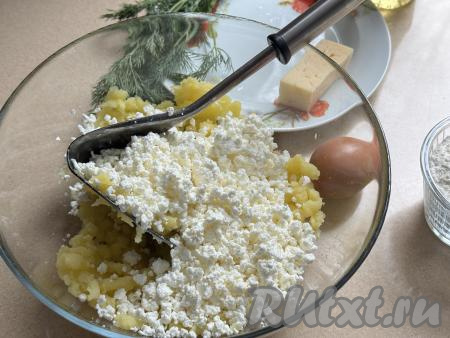 В миску с получившимся картофельным пюре выложить творог, растолочь толкушкой до однородности.